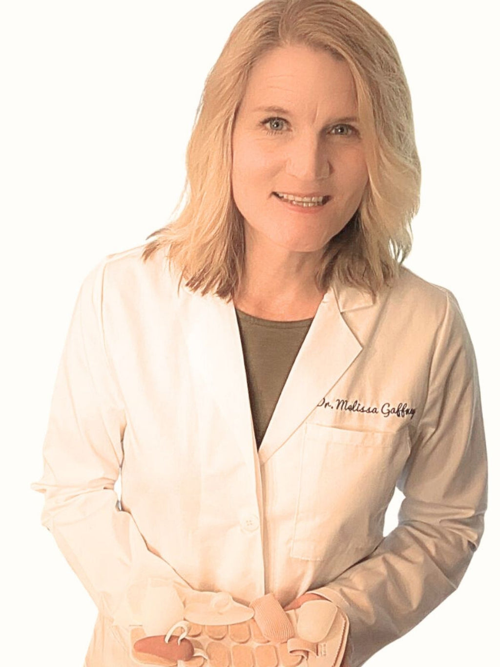 Dr. Melissa Gaffney in her white coat holding a selection of foot pads