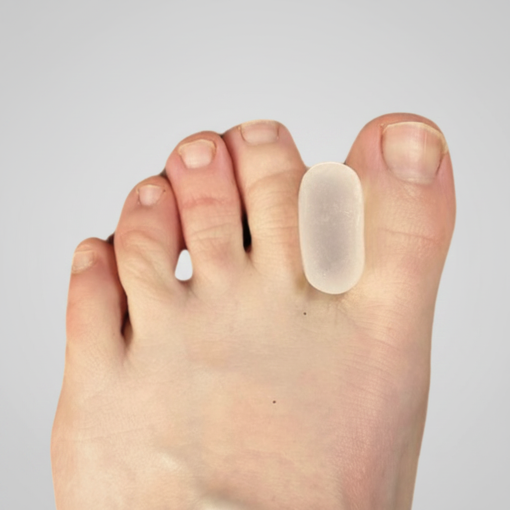 A close-up of a human foot wearing a translucent gel toe spacer over the second toe, set against a plain light background.